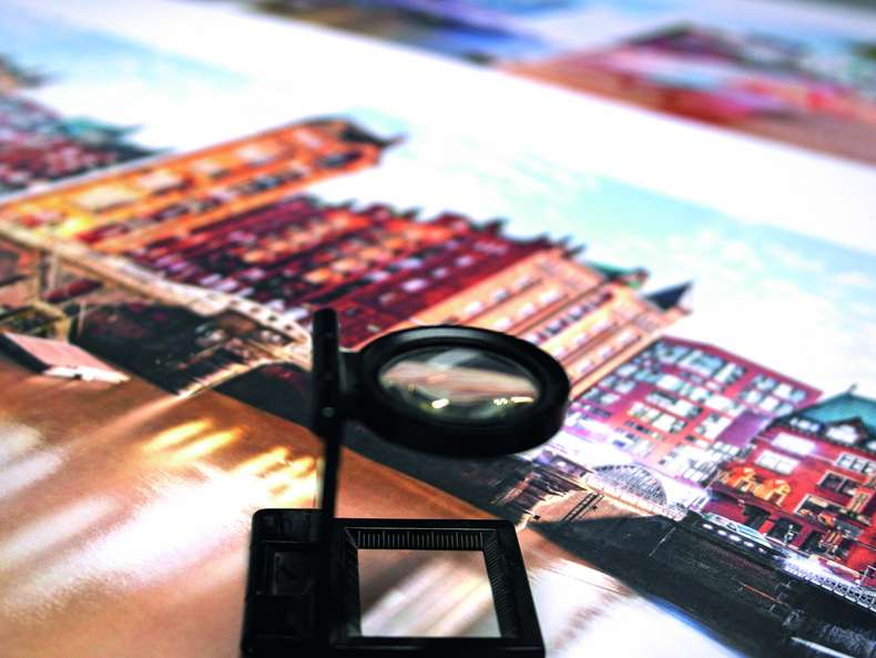 Qualitätsdruckerei PSO-Druck Vergrößerungsglas auf gedrucktes Druckerzeugnis mit Häuserfront - PSO-Druck