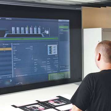 Bildschirm von der Offsetdruckmaschine Druckerei Hamburg Großer Bildschirm von Offsetdruckmaschine, Mensch steht davor und bedient die Technik, Druckerei Hamburg