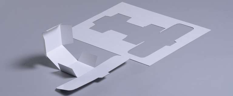 Geplottete Faltschachtel neben Papier Abfall