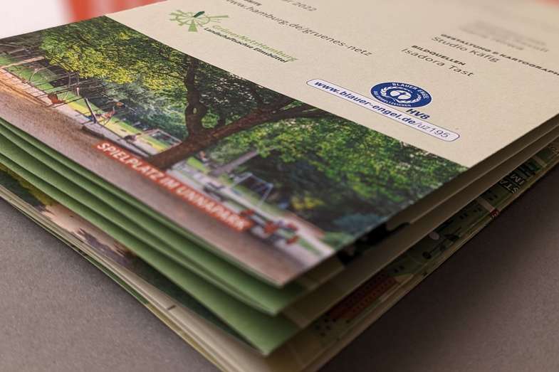 Recycling- oder Umweltpapier-Druckerei Hamburg Festes bedrucktes Papier aufeinandergelegt liegt auf braunem Untergrund - Druckerei Hamburg