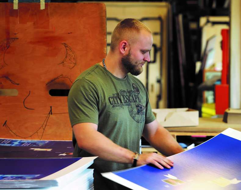 Ausbildung Person arbeitet an blau gefärbten Druckbögen in Produktionsumfeld - Ausbildung Mediengestalter Digital und Print Hamburg