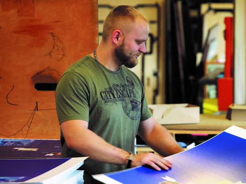 Person arbeitet an blau gefärbten Druckbögen in Produktionsumfeld - Ausbildung Mediengestalter Digital und Print Hamburg