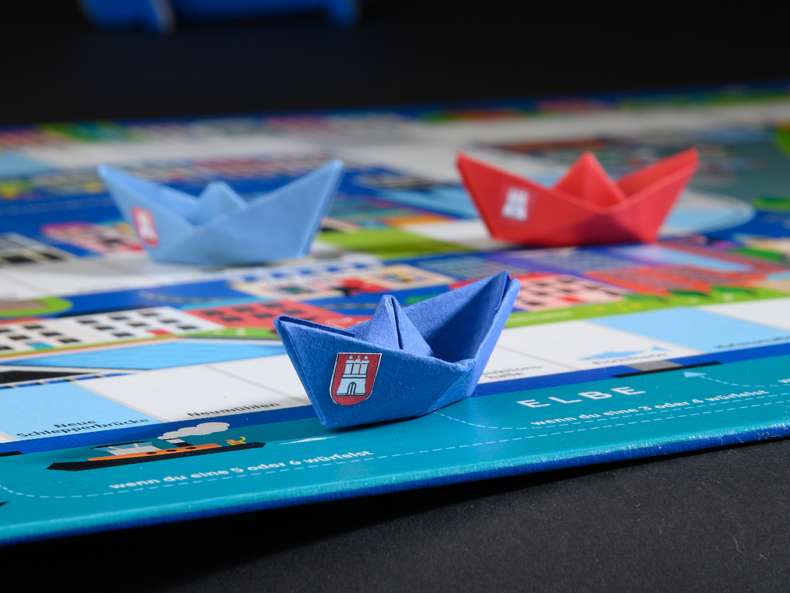Brettspiele produzieren lassen Faltböötchen auf Brettspiel, Nahaufnahme - Brettspiele produzieren lassen